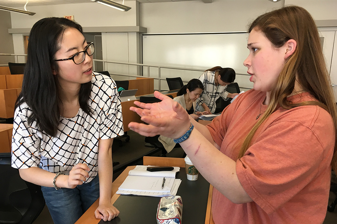 Two students talking in a large classroom